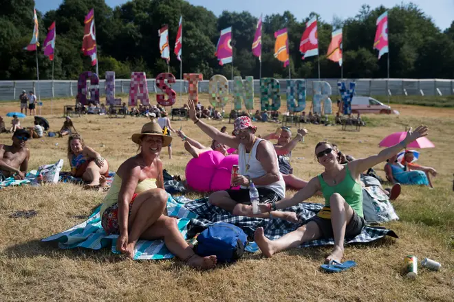 Glastonbury Festival revellers sit outside the sign on Worthy Farm