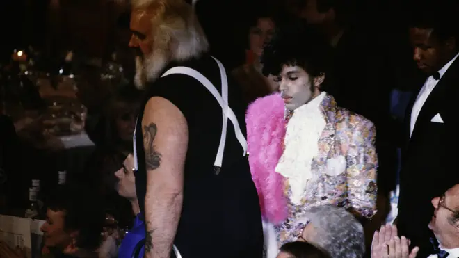Prince makes his way to collect his 1985 Best International Artist award, accompanied by his ENORMOUS bodyguard Big Chick Huntsberry.