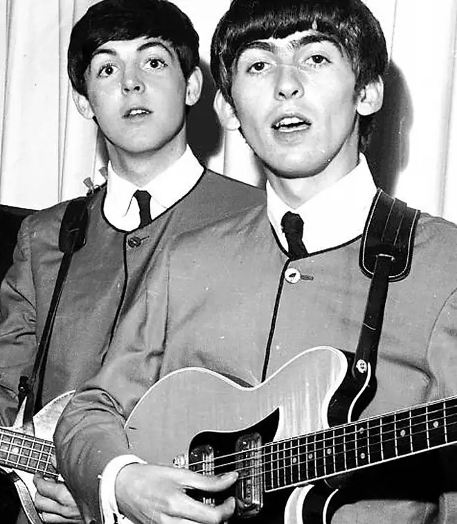 The Beatles' Paul McCartney and George Harrison holding guitar up for auction