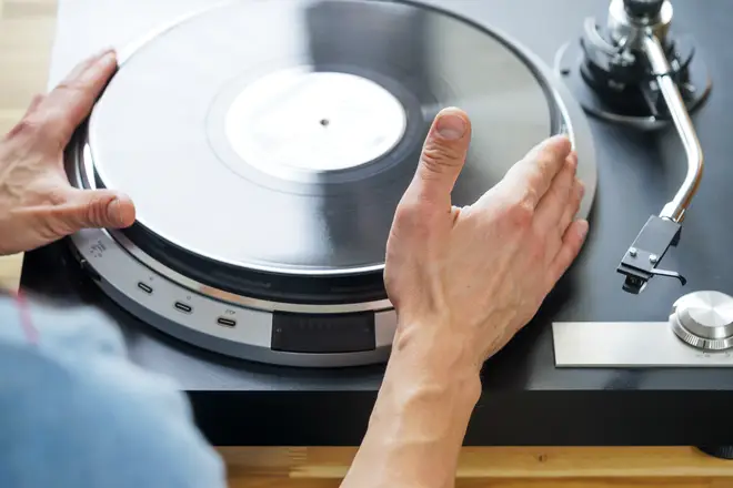 Hands placing vinyl on turntable