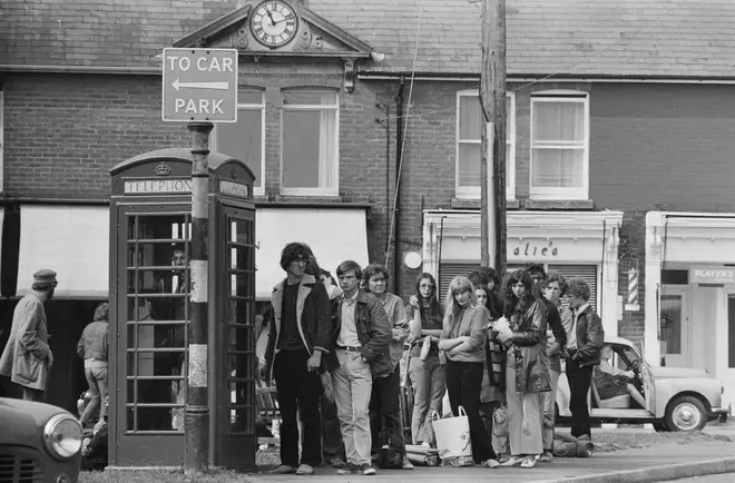 Festival-goers queuing up to make phone calls outside a red telephone box on the Isle of Wight while attending the Isle of Wight Festival, UK, 26th-31st August 1970