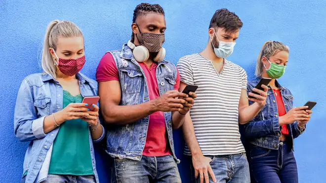Group of people using their smartphones in covid 19 times protected with face mask