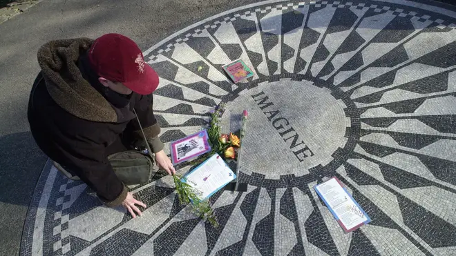 A woman lays flowers at the Imagine memorial in Central Park, opposite John Lennon's New York home at the Dakota