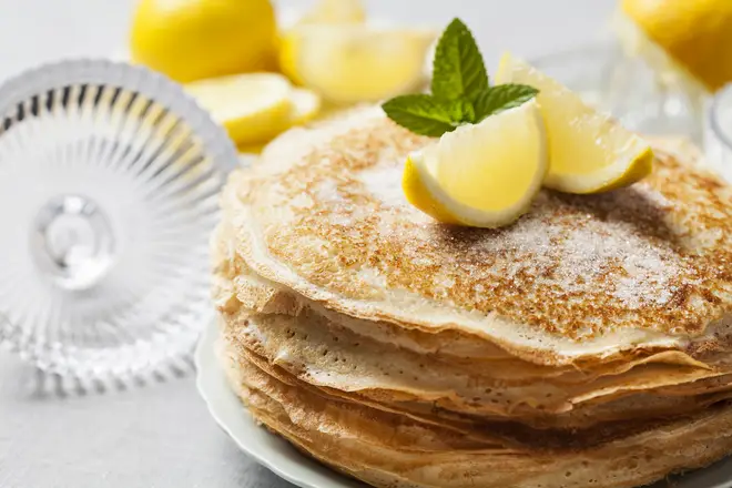 A stack of pancakes topped by slices of lemon
