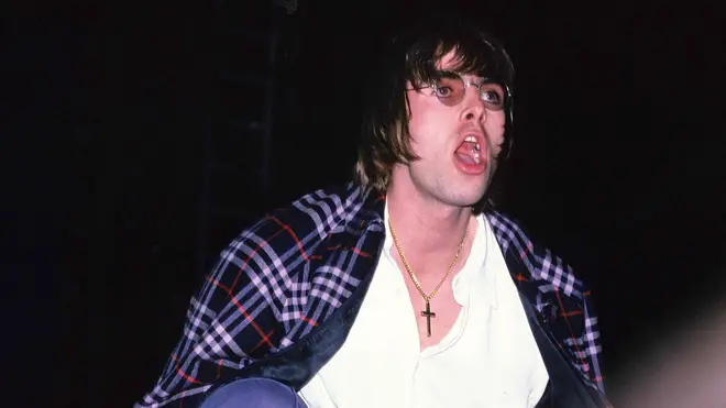 Liam Gallagher crouches at the edge of the stage on the first night at Maine Road, 27 April 1996