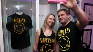 Fans pose with t-shirts depicting the Nirvana "smiley face" logo at the "Growing Up Kurt" exhibition in Ireland, 2018