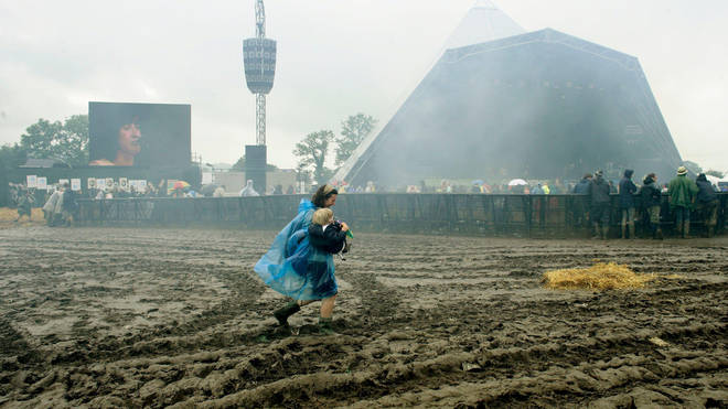 A mother carries her child through the mud during Glastonbury 2007
