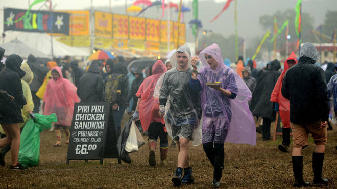 Festival goers walking through the rain at the Glastonbury Festival at Worthy Farm, Pilton on June 26, 2015