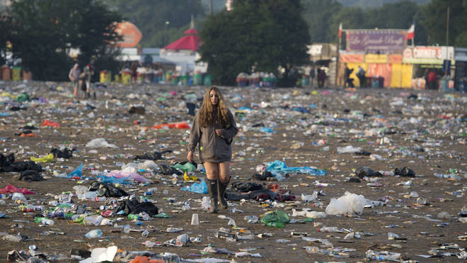 A reveller picks her way through discarded litter as she leaves the Glastonbury Festival in 2015