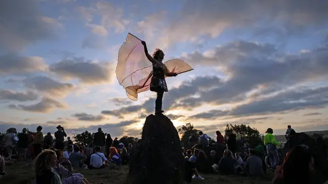 A festival-goer dances during sunset at the stone circle during Glastonbury 2019