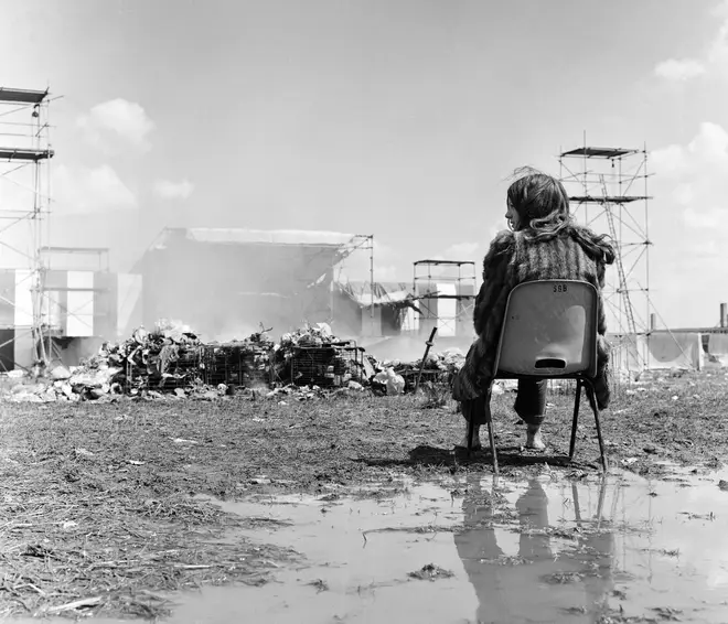 Last of the festival goers sitting among the mud and the rubbish as workmen clear up the mess at the end of Reading Festival. 26th June 1971.