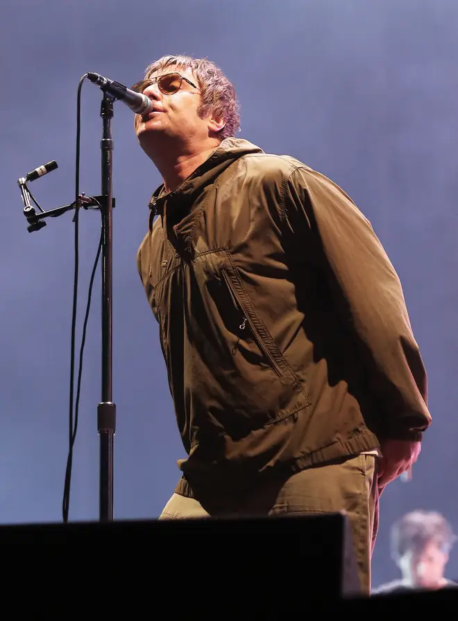 Liam Gallagher sings in his iconic stance with his hands behind his back in 2023