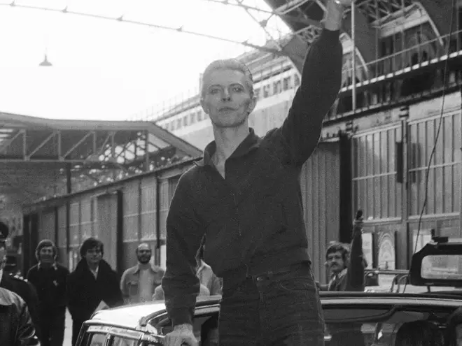 David Bowie waves to fans as he arrives at Victoria Station May 1976