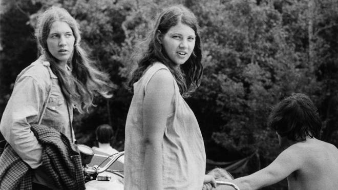 A pregnant woman and her friend wait as a motorcycle is unhitched from a car, as they prepare to leave Max Yasgur's Bethil farm and the Woodstock music festival.