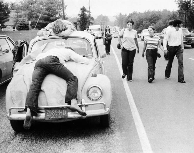 Two festival goers that found Woodstock too much lay passed out on the bonnet and roof of their Volkswagen Beetle